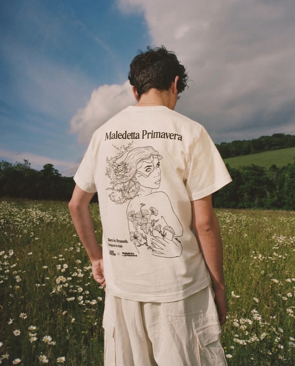 The Maledetta Primavera x Maelstrom limited tee, worn from behind in a field of daisies